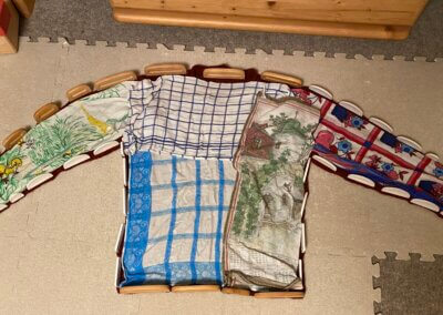 Aufgespannter Strickpulli auf zusammengesetzten Spannmatten, in Form gezogen mit Spann-Kämmen. Der gesamte Pulli ist mit (feuchten) Handtüchern bedeckt