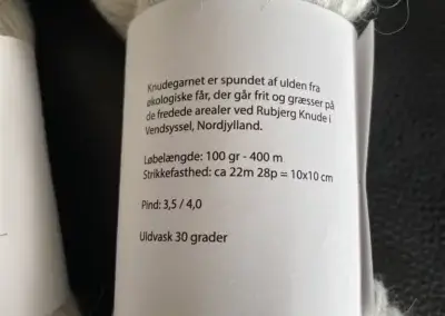 Die Rückseite des Etiketts von Knudegarn (übersetzt): Lauflänge: 100 gr - 400 m, Maschenprobe: c.a. 22 Maschen 28 REihen = 10 x 10 cm, Nadelstärke 3,5 / 4,0, waschen bei 30 Grad