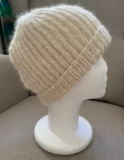 Eine sehr flauschige Mütze mit Umschlag aus wollweißem Alpaka-Garn im Patentmuster gestrickt