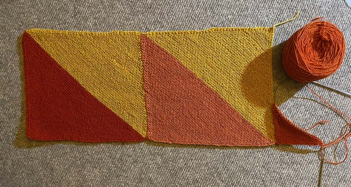 Der Anfang des Prism Blanket aus Purl Sohos „Good Wool“ Unfertiges Strickstück ("UFO") aus zwei diagonal gestrickten Quadraten mit einem Farbwechsel von Gelb zu einem Rotton